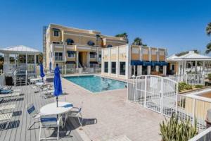 a building with a pool and a patio with tables and chairs at Atrium Condo Oceanview - Sleeps 4 Guests 107 in Cape Canaveral