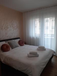 a bedroom with a large white bed with towels on it at Apartman Kristal in Sremska Mitrovica