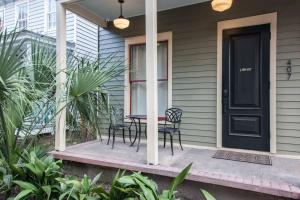 a porch with a table and chairs and a black door at Intimate Library Studio - Minutes to Forsyth Park in Savannah