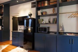 uma cozinha com armários azuis e um frigorífico preto em Intimate Library Studio - Minutes to Forsyth Park em Savannah