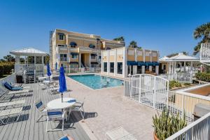Una piscina con sillas y mesas y un edificio. en Patio Condo Deluxe 2br - Sleeps 5 Guests 312, en Cabo Cañaveral