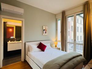 a bedroom with a bed with a red pillow on it at AwesHomeItaly - The Little Beauty Studio in Pisa