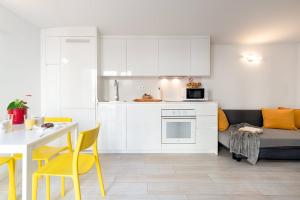 a kitchen with white cabinets and a table and yellow chairs at Castell Beach Aparthotel in Castelldefels