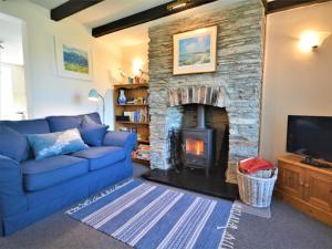 a living room with a blue couch and a stone fireplace at 2 Bed in Padstow KCOTT in Wadebridge