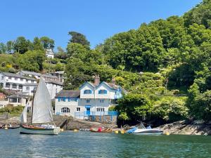 a sail boat in the water in front of a house at Fowey River Views in Fowey