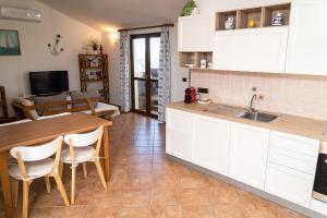 cocina con armarios blancos, mesa y comedor en Casa Madì, en Porto Torres