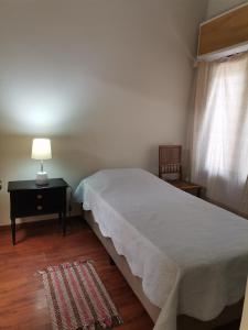 1 dormitorio con 1 cama y 1 mesa con lámpara en Flor de Loto, en Durazno