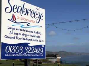 a sign for a restaurant with the ocean in the background at Seabreeze in Torquay