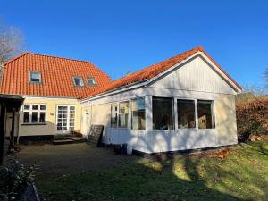 una pequeña casa blanca con techo naranja en Jelling en Jelling