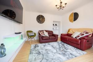 a living room with a red couch and a chair at Entire 3 bedrooms home away from Home in Salford in Manchester