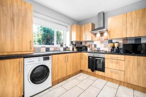a kitchen with wooden cabinets and a washer and dryer at Hotel comforts & home conveniences -sleeps 8 in Birmingham