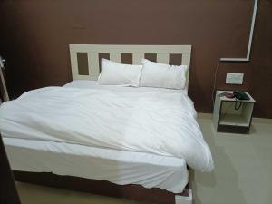 a bed with white sheets and pillows in a room at OYO IAE566 Neelkanth Hotel in Rewāri