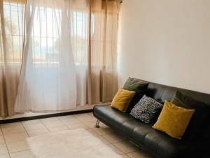 a black leather couch in a living room with a window at Frente al mar loft in Puntarenas