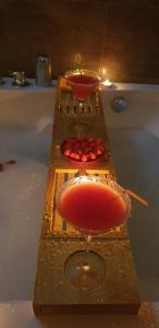 a bath tub with two glasses of red liquid at Appart'moderne in Casseneuil