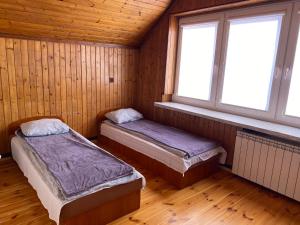 two beds in a room with two windows at Pokoje Zielonka in Zielonka