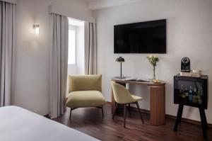 Pokój hotelowy z łóżkiem, biurkiem i telewizorem w obiekcie Maison Roma Piazza di Spagna UNA Esperienze w Rzymie