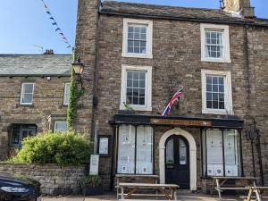 an old brick building with two picnic tables in front of it at Brook Cottage Askrigg in Askrigg