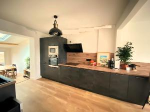 eine Küche mit schwarzen Schränken und einer Arbeitsplatte in der Unterkunft Maison 4 chambres au calme beau jardin et studio in Cagny