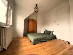 Schlafzimmer mit einem Bett und Holzboden in der Unterkunft Maison 4 chambres au calme beau jardin et studio in Cagny