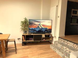 a living room with a flat screen tv on a stand at Maison 4 chambres au calme beau jardin et studio in Cagny