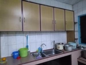La cuisine est équipée d'un évier et de placards en bois. dans l'établissement Sibu Homestay Tekam, à Sibu