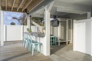 a patio with a bar with blue stools at Kind Of A Big Deal Brunswick Vacation Rentals Private home with pool and elevator in Holden Beach