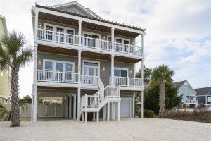 a large house with a balcony and a white chair at Kind Of A Big Deal Brunswick Vacation Rentals Private home with pool and elevator in Holden Beach