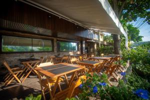 um grupo de mesas e cadeiras de madeira num pátio em Hotel Barra da Lagoa by Latitud Hoteles em Búzios