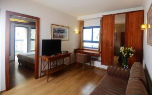 een woonkamer met een bed en een bureau met een televisie bij Abratel Suites Hotel in Tel Aviv