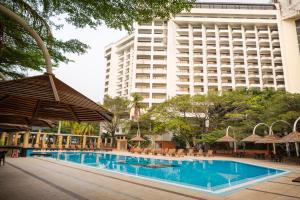 una piscina dell'hotel con un grande edificio sullo sfondo di Eko Hotel Gardens a Lagos