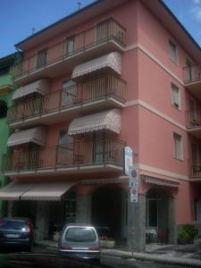 een roze gebouw met balkons en auto's geparkeerd voor het bij Hotel Corallo in Moneglia