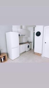 Precioso apartamento en Gandía في Playa de Gandia: مطبخ أبيض مع ثلاجة وميكروويف