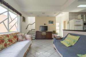 uma sala de estar com um sofá e uma televisão em Bela casa com piscina no centro de Penha/SC BSL190 em Penha