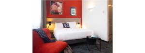 a hotel room with a bed and a red wall at Mercure Hotel Forbach Centre de Loisirs in Forbach