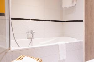 a white bathroom with a tub and a sink at Mercure Hotel Forbach Centre de Loisirs in Forbach