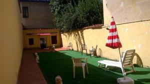 a patio with chairs and an umbrella and a lawn at Colonna Home in Florence