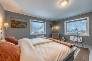 a bedroom with a large bed and two windows at Reine Fishermans House - Mountain & Seaview in Reine