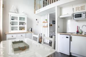 une cuisine avec des placards blancs et une table avec un tiroir dans l'établissement Les Mouettes Appartement cosy avec piscine, à Saint-Martin-de-Ré