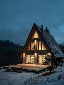 a large wooden house with windows in the snow at Lagom Lodge in Izvoare