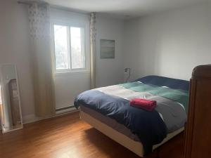 ein Schlafzimmer mit einem Bett mit einem roten Objekt darauf in der Unterkunft Appartement près du Métro in Laval