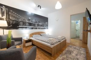 a bedroom with a bed and two chairs at V & V Studio Apartments 2 in Niš