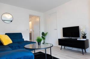 a living room with a blue couch and a table at Stylish House with Private parking in Glasgow