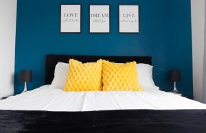 a bedroom with a bed with yellow pillows and a blue wall at Stylish House with Private parking in Glasgow