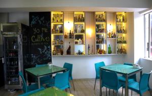 a restaurant with two tables and blue chairs and shelves with bottles at Hotel Sixtina Plaza Medellin in Medellín