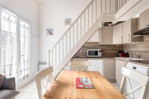 una cocina con una mesa de madera y una escalera en Appartement Océanis avec Piscine proche du port, en Saint-Martin-de-Ré