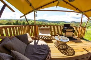 a wooden deck with a couch and an umbrella at Camping et Lodges de Coucouzac in Lagorce
