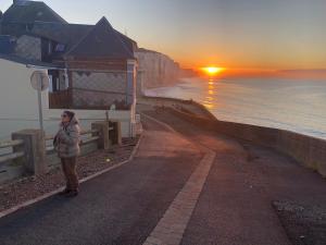 een vrouw die op een weg staat en naar de zonsondergang kijkt bij villa stella in Ault