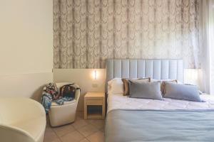 una camera con un grande letto e una sedia di Hotel Athena a Cervia
