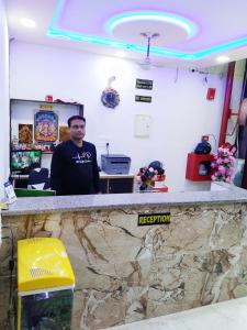 a man standing behind a counter in a room at OYO S S Palace in Agra