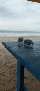 un par de gafas sentadas en una mesa en la playa en Hostal Villa Brisa en Ballenita